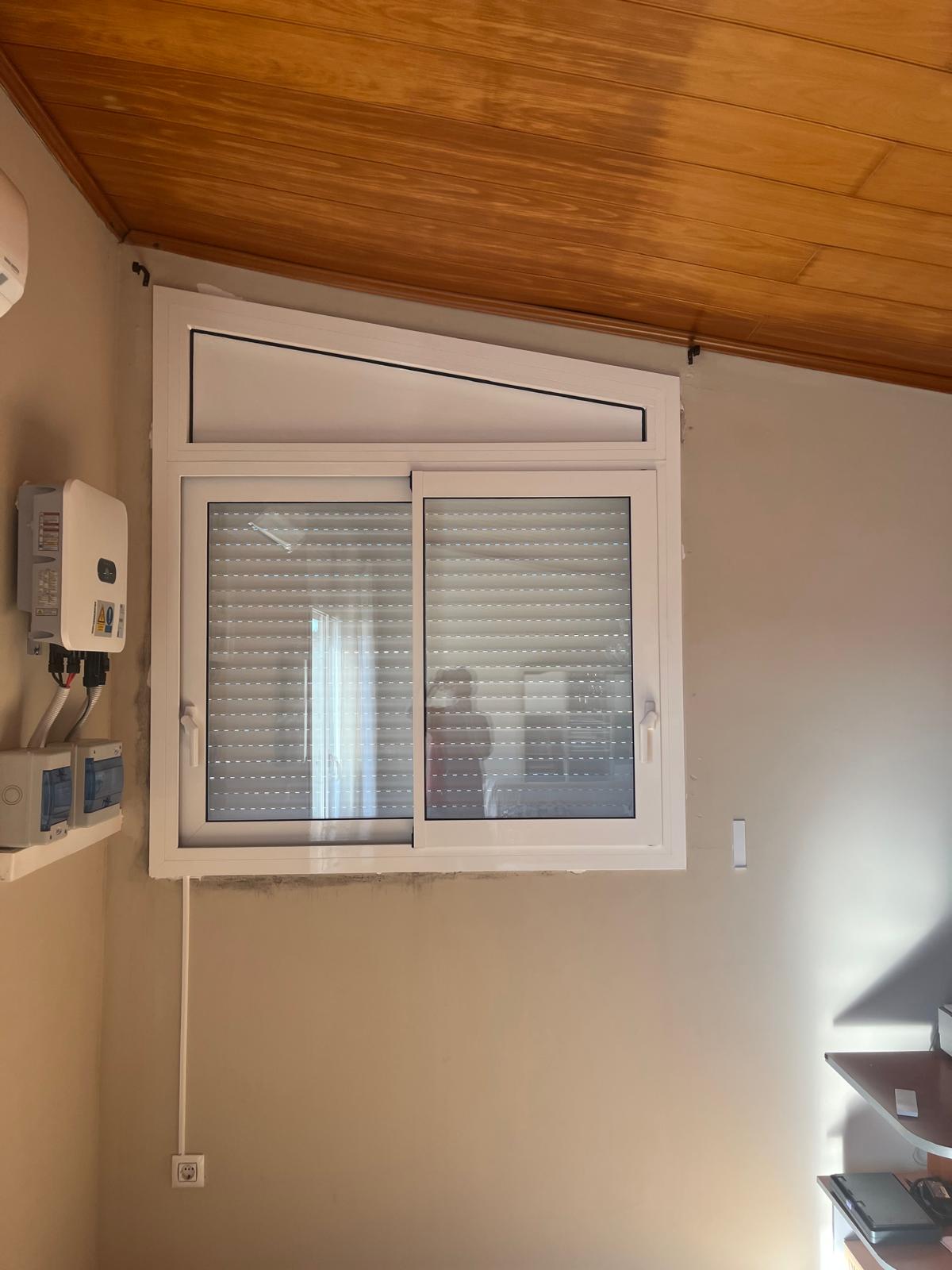 Ventana corredera blanca con fijo superior adaptado al techo inclinado en Girona
